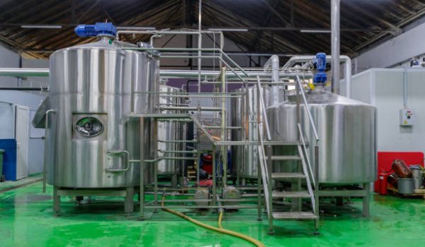 Large steel tanks with pumps and pipeline in production line of a brewery