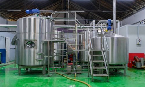 Large steel tanks with pumps and pipeline in production line of a brewery